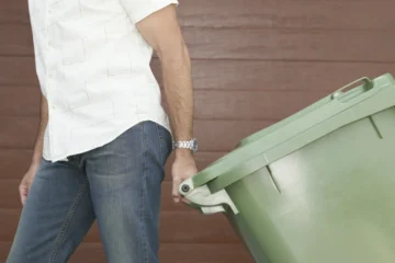 mężczyzna ciągnie pojemnik na odpady
